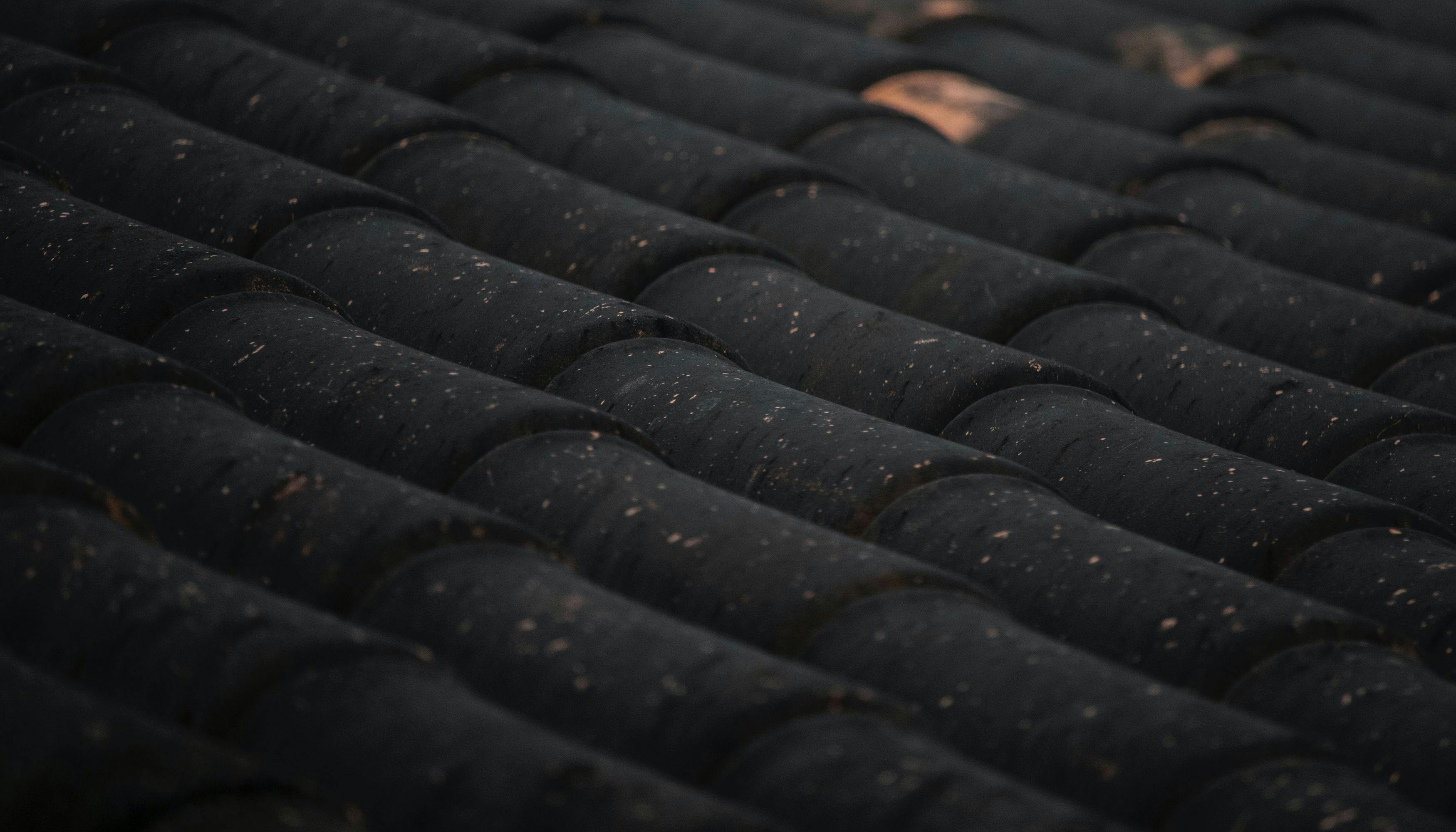 Close-up of a black roof with various tiles, some missing.