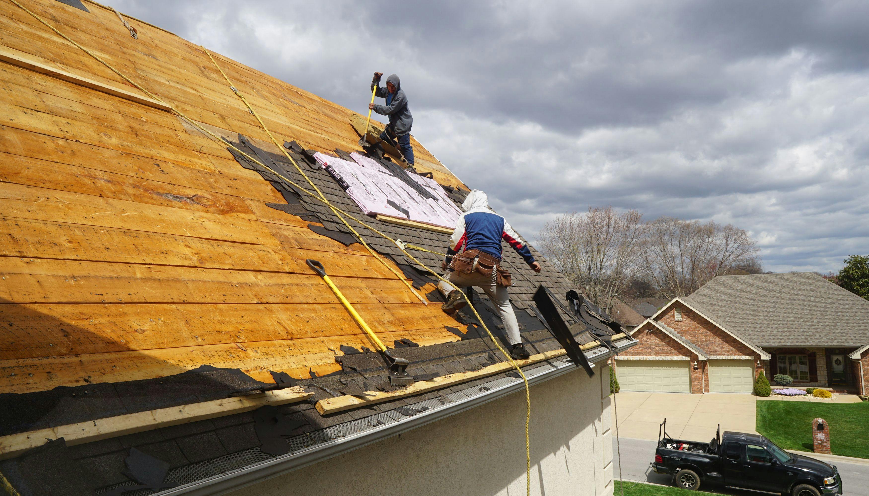 Roofers removing old roof during renovation process.